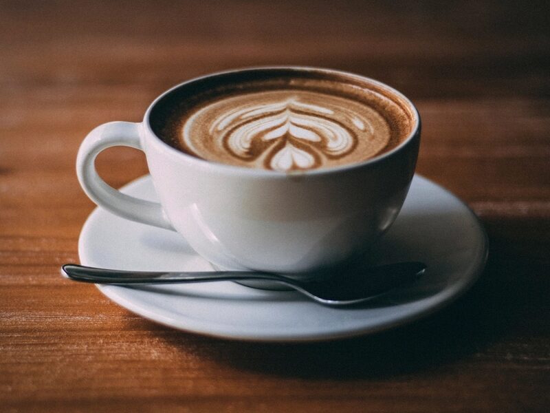 木のテーブルに置かれたラテアートのコーヒー